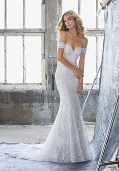 a woman in a wedding dress posing for the camera with her hand on her hip