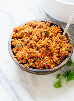 a bowl filled with rice and garnished with cilantro on the side