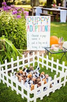 there is a sign that says puppy adoptions in the grass with stuffed animals inside