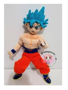 a crocheted dragon doll with blue hair and orange pants is posed on a white surface