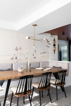 a dining room table with four chairs and a bench in front of it, next to a couch