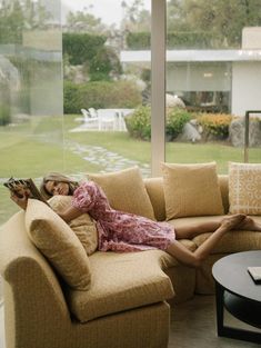 a woman laying on top of a couch next to a table with a book in it