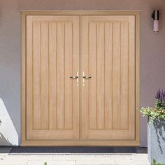 two wooden doors on the side of a house next to potted plants and flowers