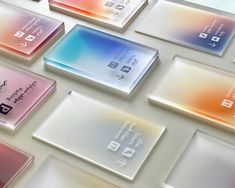 many different colored glass business cards are arranged on a white surface with the same color as each other