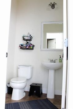 a white toilet sitting next to a sink in a bathroom under a mirror on the wall