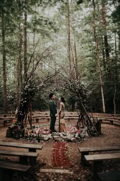 a couple standing in the middle of a forest