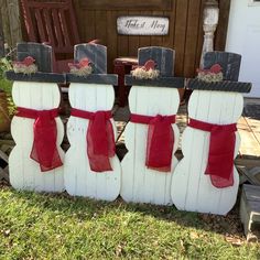 three snowmen made out of pallets with red bows on them sitting in front of a door