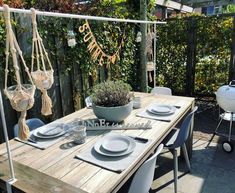 a wooden table with plates and silverware on it in front of an outdoor grill