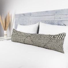 a white bed topped with pillows next to a wooden headboard