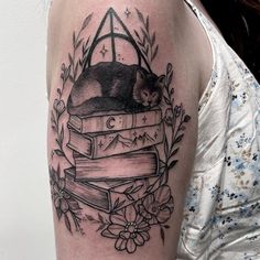 a woman with a tattoo on her arm has a cat sleeping on top of books