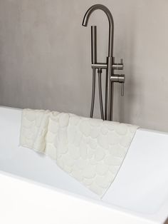 a white bath tub sitting next to a metal faucet