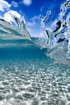 an underwater view of the ocean with clear water and blue sky in the back ground