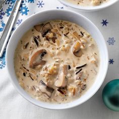 two bowls filled with soup on top of a blue and white table cloth next to silver spoons