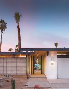 a modern house with palm trees in the front yard and driveway leading to it's entrance