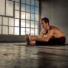 a shirtless man sitting on the floor in front of a window