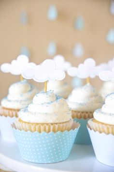 cupcakes with white frosting and blue sprinkles are on a plate