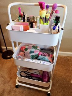 a white cart filled with lots of makeup and hair products on top of carpeted floor