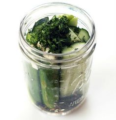 a jar filled with cucumbers and herbs