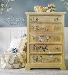 a dresser with butterflies painted on it and a chair in front of the wall behind it