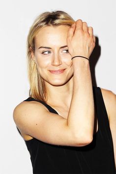 a woman posing with her hand on her head and looking at the camera while wearing a black top