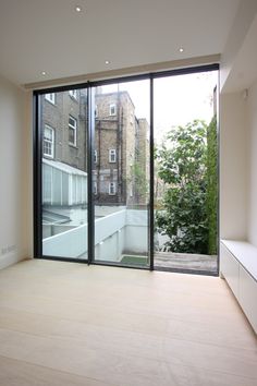 an empty room with large glass doors leading to a balcony and trees in the background