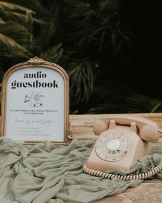 an old fashioned phone sitting on top of a blanket next to a sign that reads audio guestbook