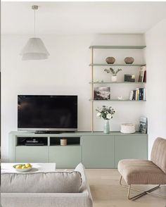 a living room filled with furniture and a flat screen tv on top of a wooden shelf