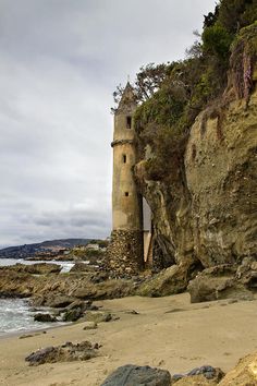 an old tower on the side of a cliff by the ocean