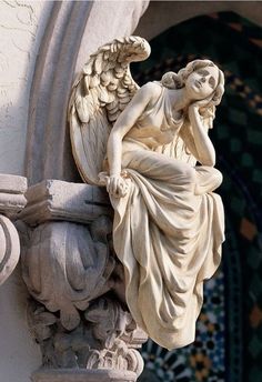 an angel statue sitting on the side of a building