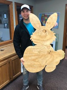 a man holding up a wooden cut out of a bunny