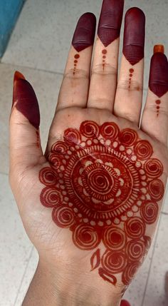 a woman's hand with red henna on it