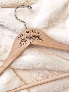 a wooden hanger with the name mrs mccy on it sitting on a white blanket