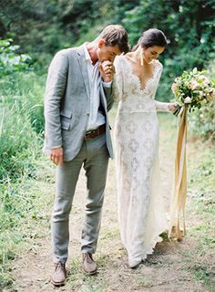 a couple standing next to each other in front of trees