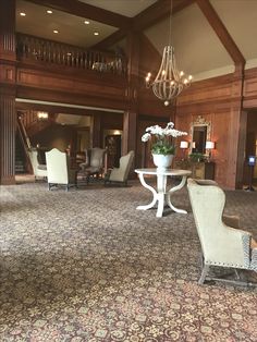 an elegant living room with chandelier, chairs and flowers on the coffee table