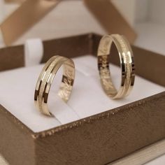 two gold wedding rings sitting in a box