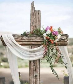 a wooden cross decorated with flowers and greenery