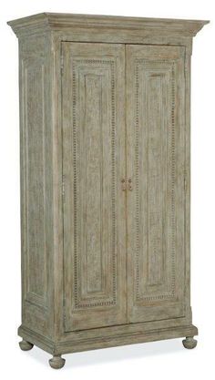 the armoire is made from wood and has carvings on it's sides, along with