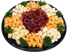 a platter with cheese, grapes and broccoli arranged in the shape of a heart