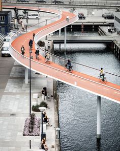 people are riding bikes on a bridge over the water