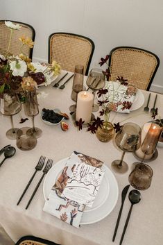 the table is set with plates, silverware and candles for an elegant dinner party