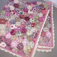 two quilts are laying next to each other on a tablecloth that is covered in pink and white flowers