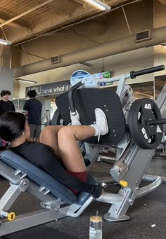 a woman sitting on top of a bench next to a gym equipment machine in a building