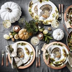 a table set for thanksgiving with turkey plates and silverware