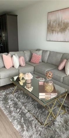 a living room with grey couches and pink pillows