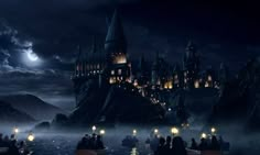 hogwart's castle is lit up at night with candles floating in the water