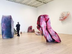 a person standing in an art gallery looking at artwork on the wall and floor,