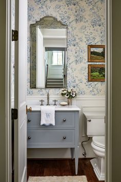 the bathroom is decorated in blue and white with floral wallpaper on the walls, along with an antique vanity