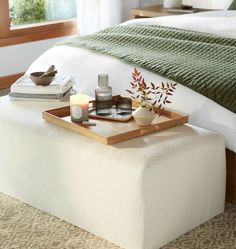 a tray with candles on top of a footstool in a bedroom next to a bed