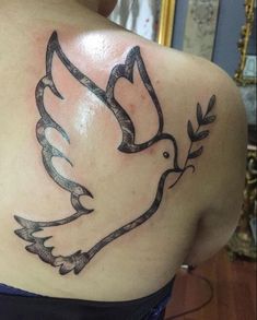 the back of a woman's shoulder with a bird tattoo on her left side