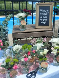 there are many vases with flowers in them on the table next to the pool